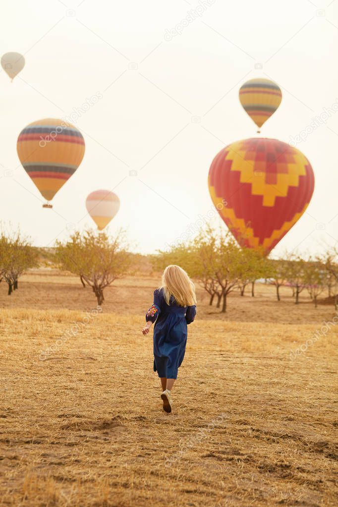 Woman Running In Field With Hot Air Balloons Flying 