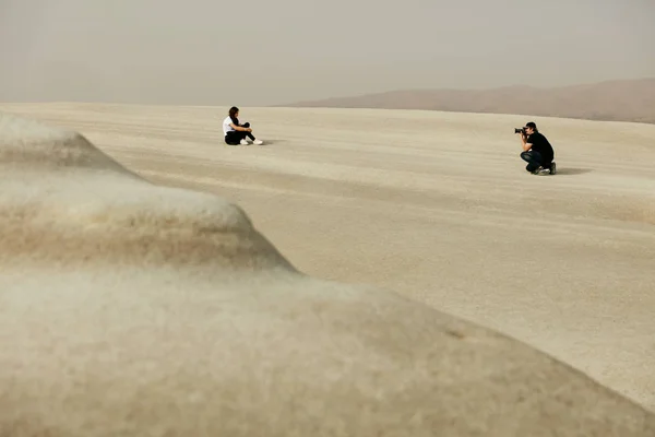 Hombre tomando fotos de mujer en la colina de arena en el desierto . —  Fotos de Stock