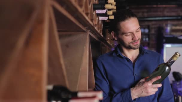 Красавчик держит бутылку вина в винном погребе — стоковое видео
