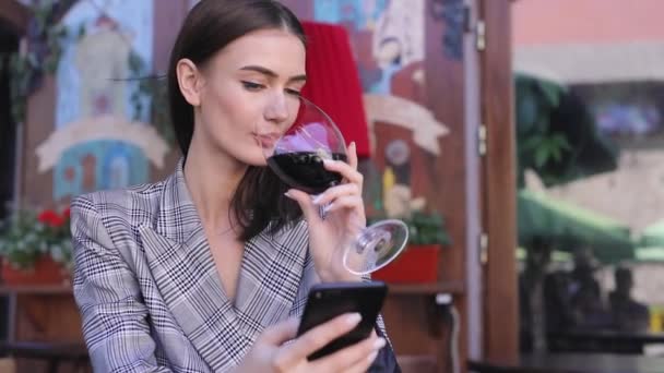 Lachende vrouw drinken van wijn en het gebruik van de telefoon in Restaurant — Stockvideo