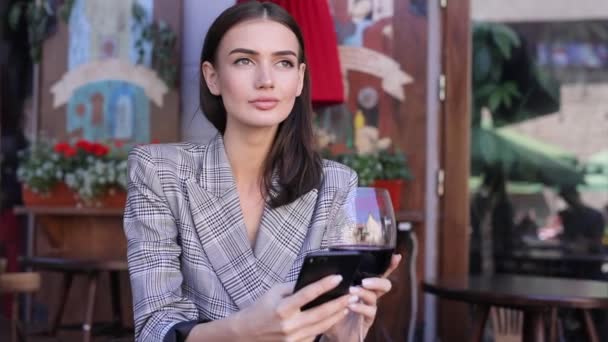 와인을 마시는 고 식당에 전화를 사용 하 여 웃는 여자 — 비디오