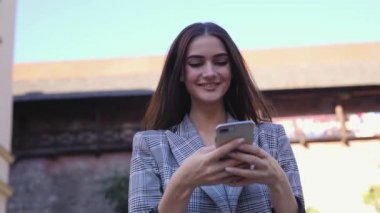 Telefonunuzun ve şehir caddede yürüyüş güzel gülümseyen kadın