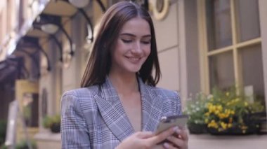 Telefonunuzun ve şehir caddede yürüyüş güzel gülümseyen kadın