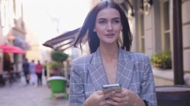 Telefonunuzun ve şehir caddede yürüyüş güzel gülümseyen kadın