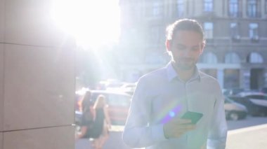 Cep telefonuyla sokakta güneşli günde iş adamı