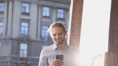 Cep telefonuyla sokakta güneşli günde iş adamı. Smartphone açık havada ile gülümseyen erkek