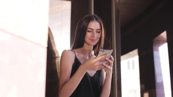 Hermosa mujer de moda usando el teléfono móvil cerca de la oficina — Vídeo de stock