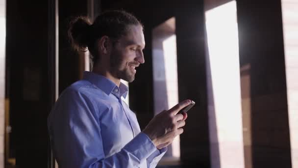 Hombre de negocios usando teléfono móvil cerca del edificio de oficinas — Vídeos de Stock