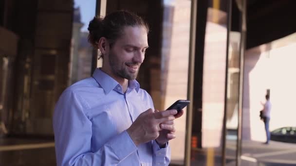 Бізнесмен використовує мобільний телефон біля офісної будівлі — стокове відео