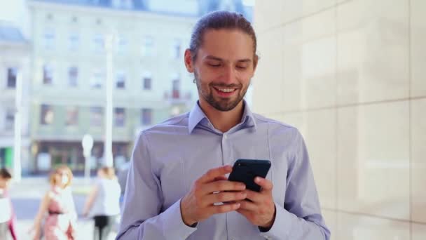 Человек, использующий мобильный телефон, отправляющий сообщения на Сити-стрит — стоковое видео