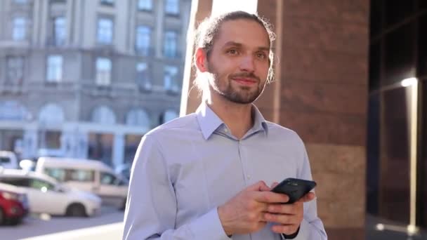 Hombre de negocios usando el teléfono móvil al aire libre en el día soleado en la calle — Vídeos de Stock