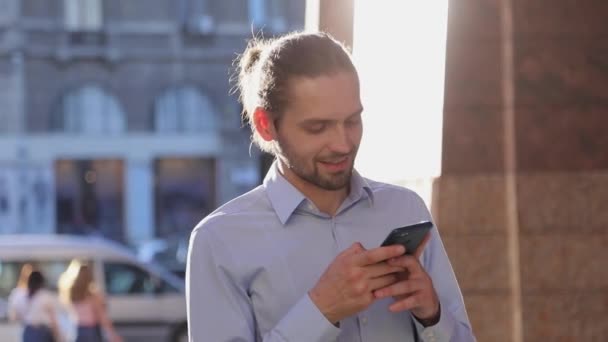 Деловой человек использует мобильный телефон на улице в солнечный день — стоковое видео