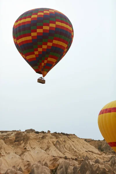 Ballon à air chaud coloré avec panier volant dans le ciel au-dessus de la terre — Photo