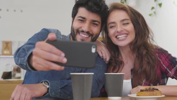 Pareja feliz con teléfono haciendo videollamada en el café . — Vídeos de Stock