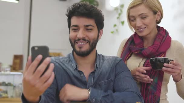 Pareja feliz con teléfono haciendo videollamada en el café . — Vídeos de Stock