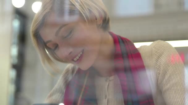 Технологія. Жінка, використовуючи телефон для спілкування в кафе в приміщенні — стокове відео