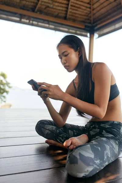 Mujer con teléfono. Chica asiática en ropa deportiva usando Smartphone —  Fotos de Stock