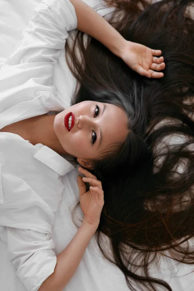 Όμορφη γυναίκα με μακριά μαλλιά, κόκκινα χείλη μακιγιάζ σε λευκό πουκάμισο — Φωτογραφία Αρχείου