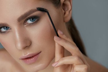 Kaş makyajı. Jel fırça closeup ile kadın fırçalama kaşları