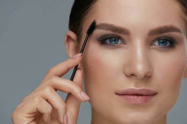 Kaş makyajı. Jel fırça closeup ile kadın fırçalama kaşları