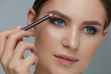 Beauty makeup. Woman shaping eyebrow with brow pencil closeup clipart