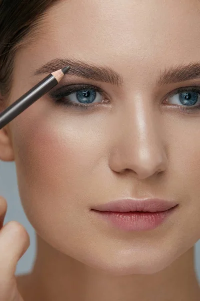 Maquillaje de belleza. Mujer dando forma a la ceja con primer plano de lápiz de frente — Foto de Stock