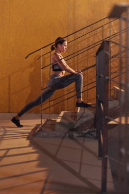 Spor yapmadan önce spor salonundaki kadın bacaklarını açıyor.