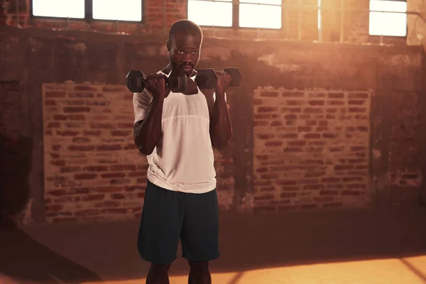 Workout. Sport man doing arm exercise with dumbbell at gym