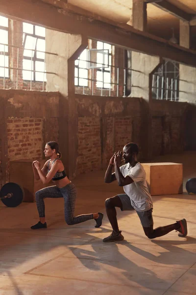 Esporte casal fazendo perna lunge exercício no ginásio — Fotografia de Stock