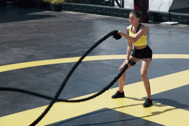 Spor kadını spor salonunda halat egzersizi yapıyor.