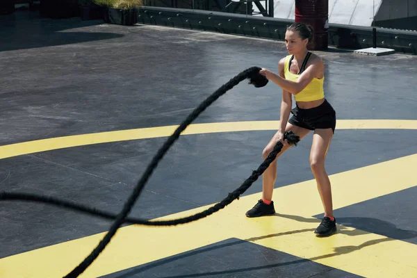 Deportiva haciendo ejercicios de cuerdas de batalla en el gimnasio — Foto de Stock