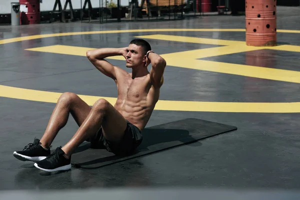 Hombre de deporte haciendo abdominales crujidos ejercicio, entrenamiento de fitness en la calle —  Fotos de Stock
