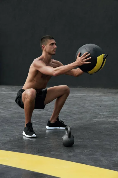 Übung. Sportmann beim Kniebeugen mit Medizinball im Fitnessstudio — Stockfoto