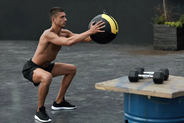 Упражнения. Спортивный человек, занимающийся спортом с мячом в спортзале — стоковое фото