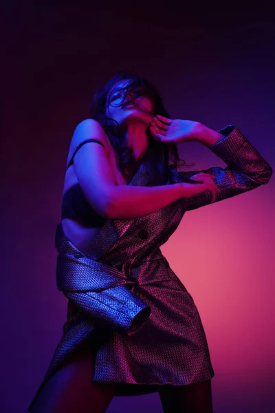 Fashion woman model in fashionable dress in neon light at studio