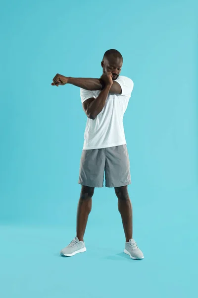 锻炼。男人伸展手臂，在蓝色背景上热身 — 图库照片