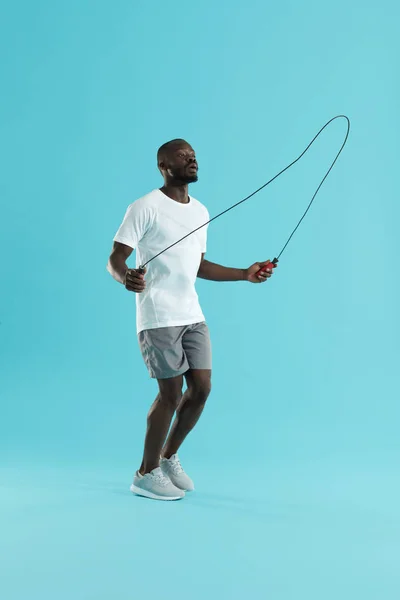 Entrenamiento. Hombre deportivo en ropa deportiva haciendo ejercicio sobre cuerda de salto — Foto de Stock