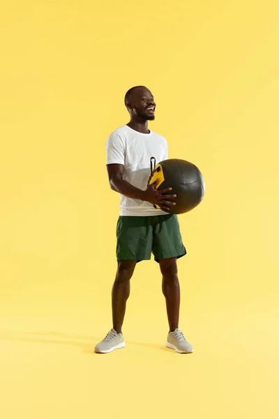 运动男子在运动穿与医疗球在黄色背景 — 图库照片