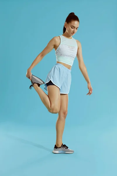 Fitness. Nő a Sportruházat nyújtó lábak, kék háttér — Stock Fotó