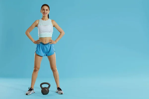 Mujer fitness con cuerpo en forma en ropa deportiva y peso de gimnasio en azul — Foto de Stock