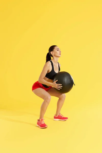 Treino de fitness. Mulher exercitando agachamentos com bola médica no estúdio — Fotografia de Stock