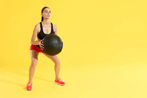 Entrenamiento de fitness. Mujer ejercitando sentadillas con pelota médica en el estudio — Foto de Stock