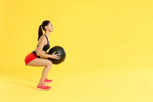Treino de fitness. Mulher exercitando agachamentos com bola médica no estúdio — Fotografia de Stock