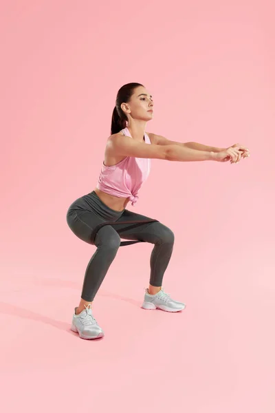 Des squats. Femme en vêtements de sport accroupi avec bande de résistance — Photo