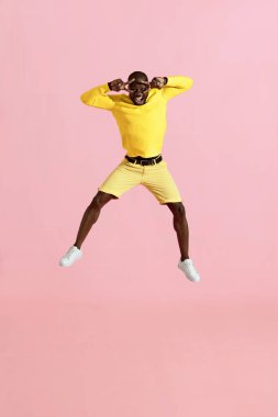 Atlamak. Mutlu adam havada zıplayıp, pembe arka planda çığlık atıyor.