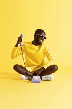 Sarı arka planda oturan stresli telefon görüşmesi olan adam