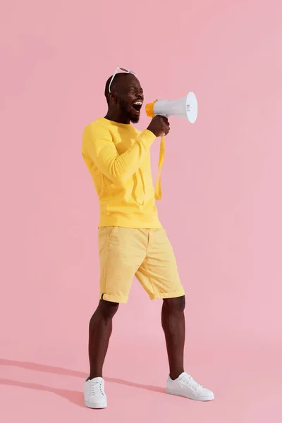 Atenção! Homem negro gritando em megafone sobre fundo rosa — Fotografia de Stock