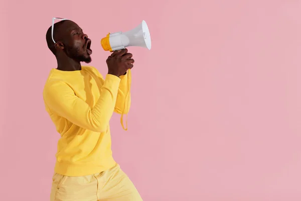 Чёрный мужчина кричит в мегафоне на розовом фоне — стоковое фото