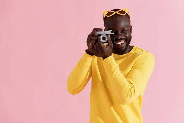 Šťastný muž fotograf s fotografickou kamerou na barevném pozadí — Stock fotografie