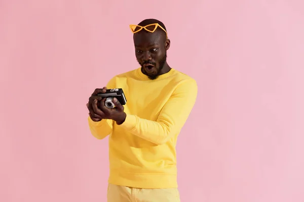 Hombre sorprendido mirando fotos en la cámara sobre fondo rosa — Foto de Stock